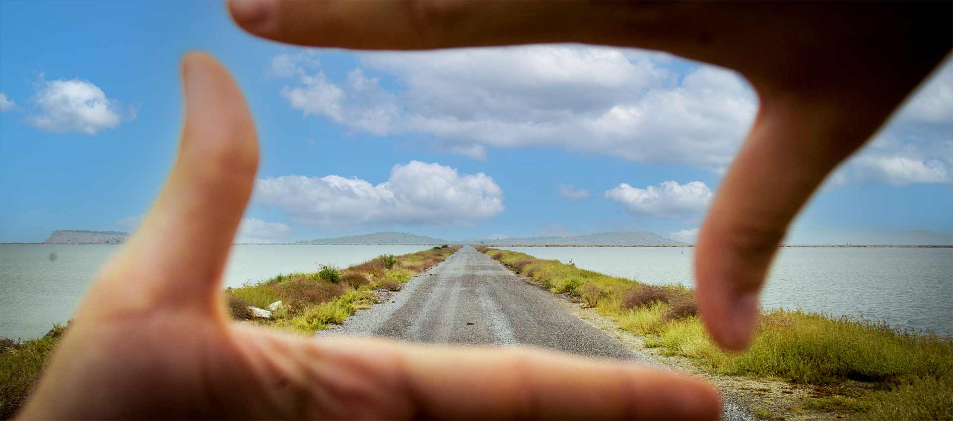 Zwei H&auml;nde rahmen den Blick auf eine Stra&szlig;e, die zum Horizont f&uuml;hrt
